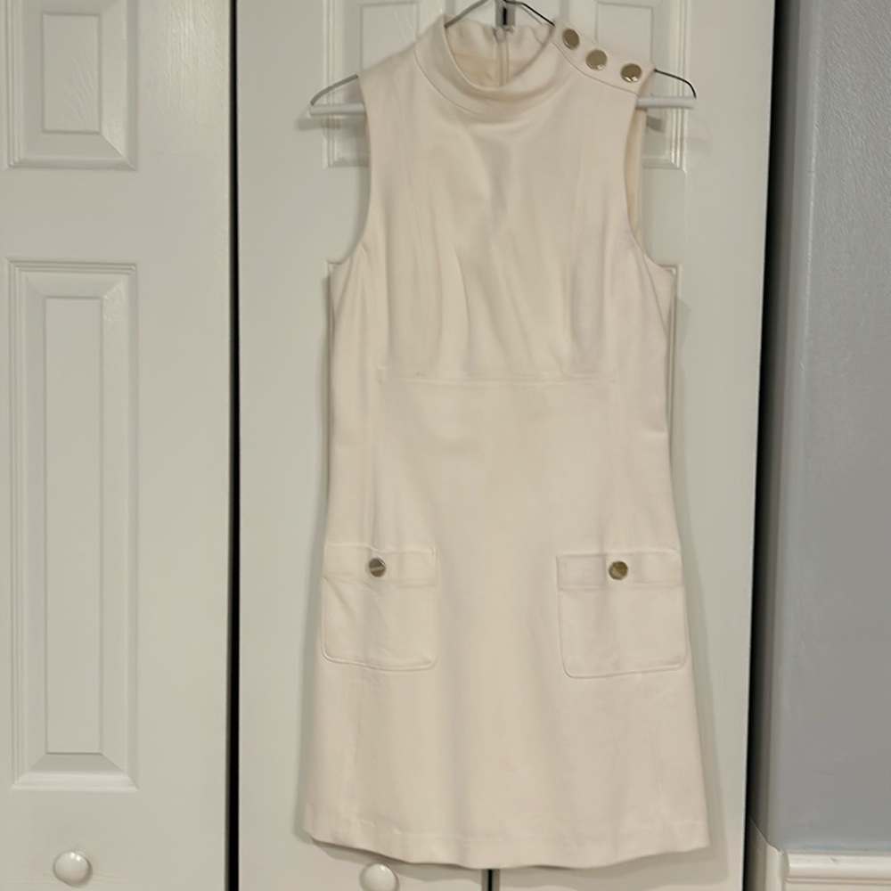off white dress with gold button detail on shoulder and front pockets.